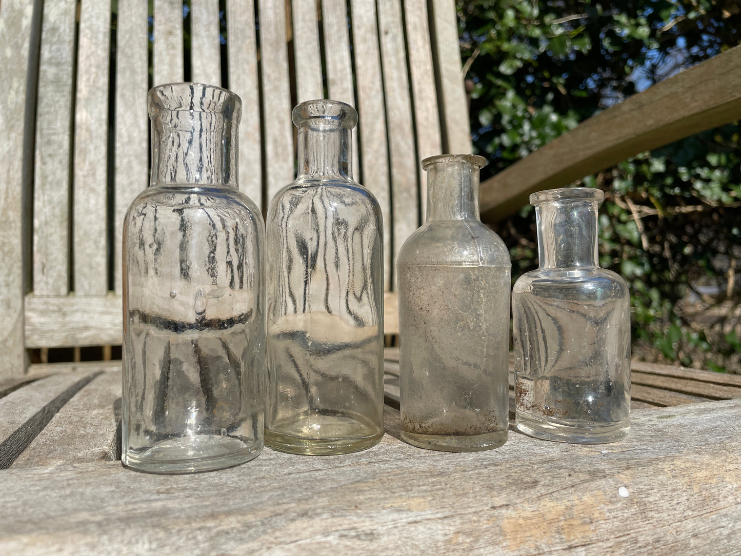 Four clear old glass medicine bottles tallest 11.5cm