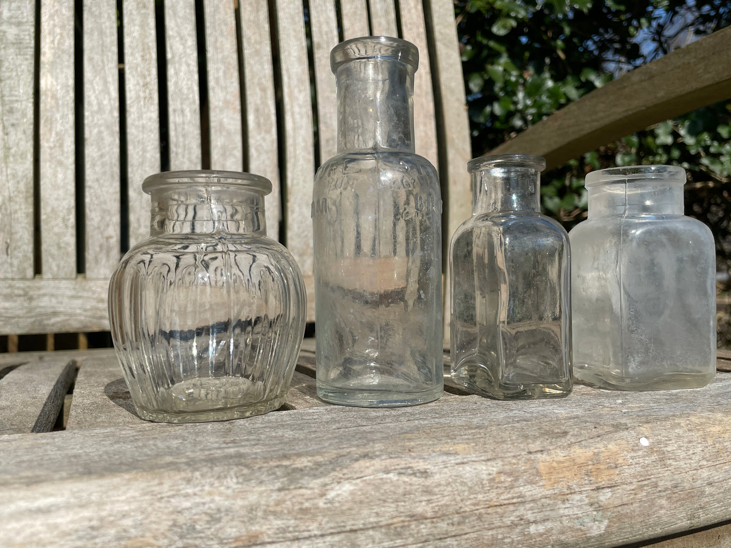 Four clear glass vintage bottles tallest 13.5cm one marked Furniture cream Stephenson Brothers