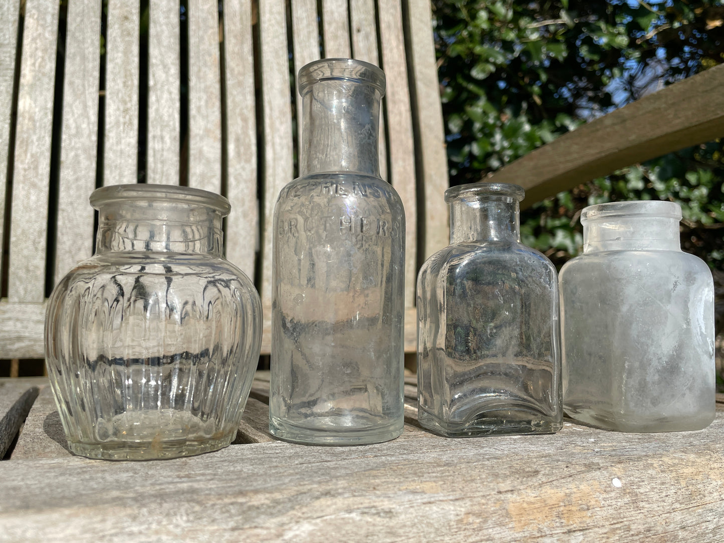Four clear glass vintage bottles tallest 13.5cm one marked Furniture cream Stephenson Brothers