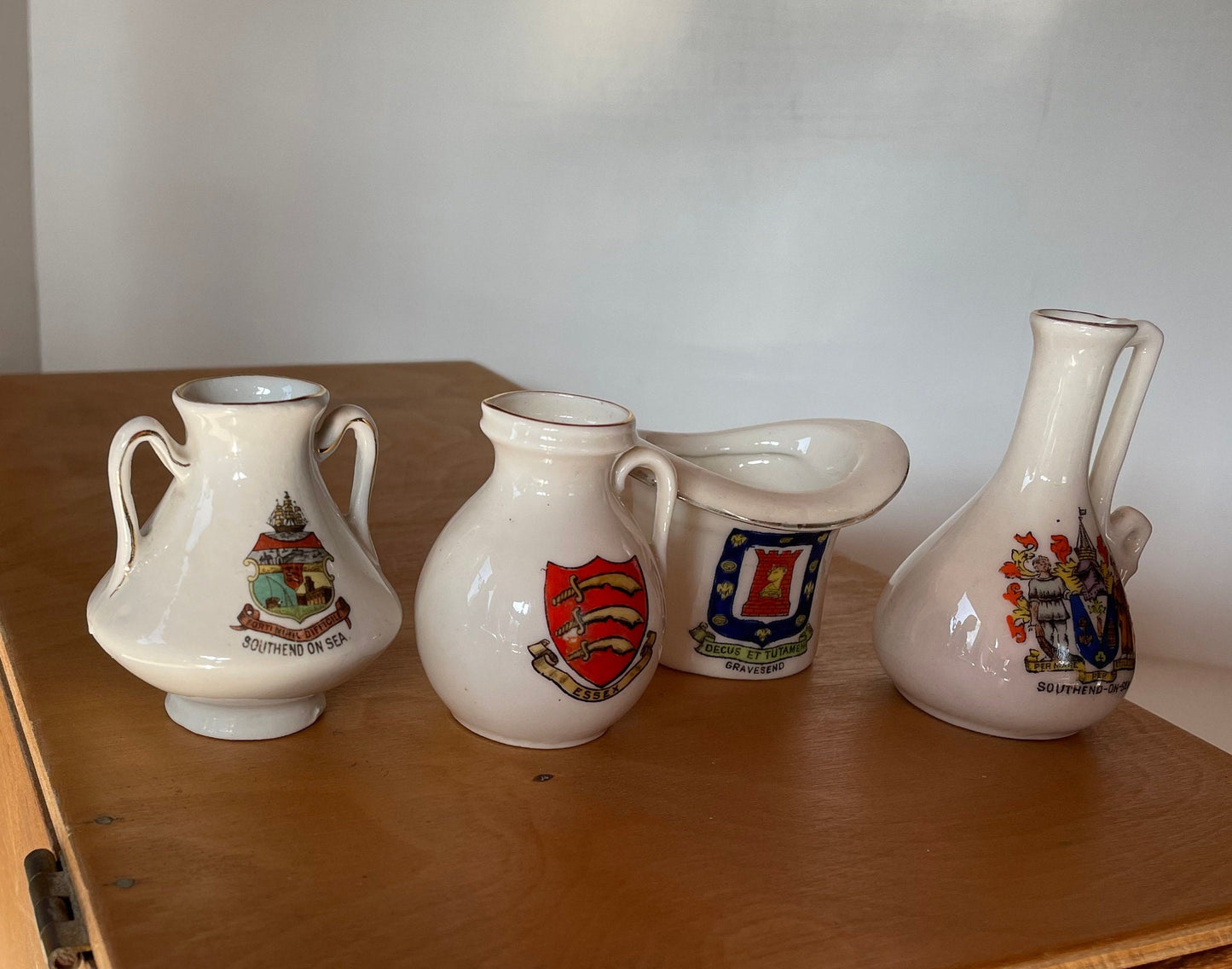 Four Crest Ware Pieces From Places Around The UK - a W.H Goss Crest Ware Essex Jug, Gravesend Top Hat, Two Southend -On -Sea Jugs