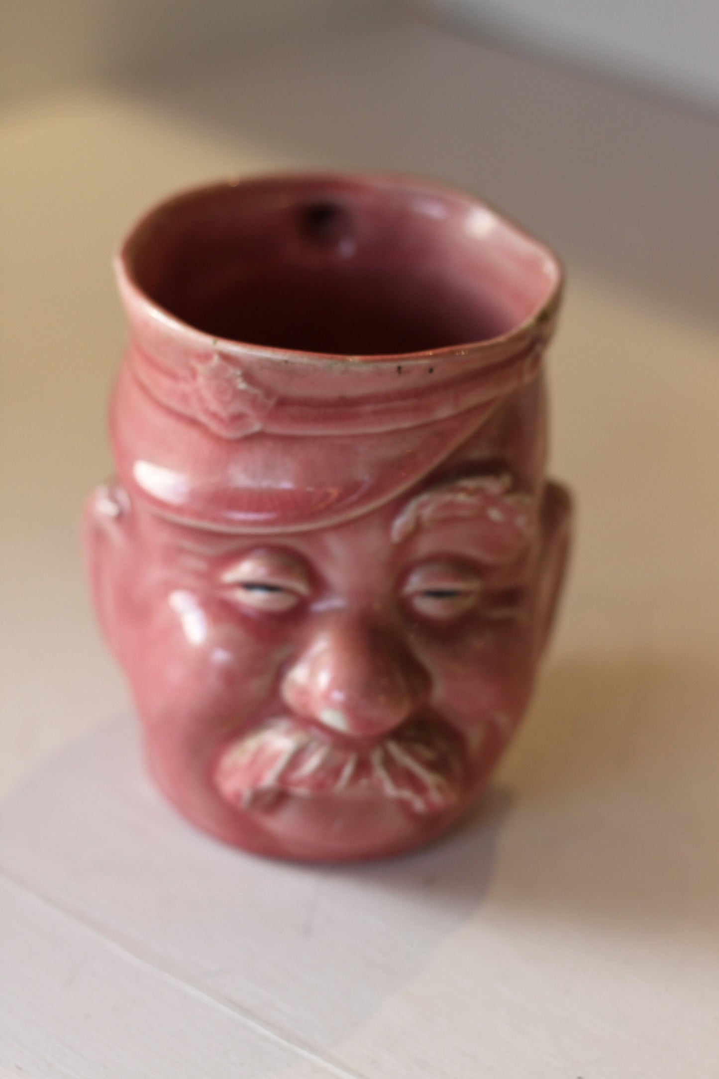 A Vintage Dusky Pink Glazed Military Mug in The Form of Bruce Bairnsfather's Old Bill, 11.5cm high