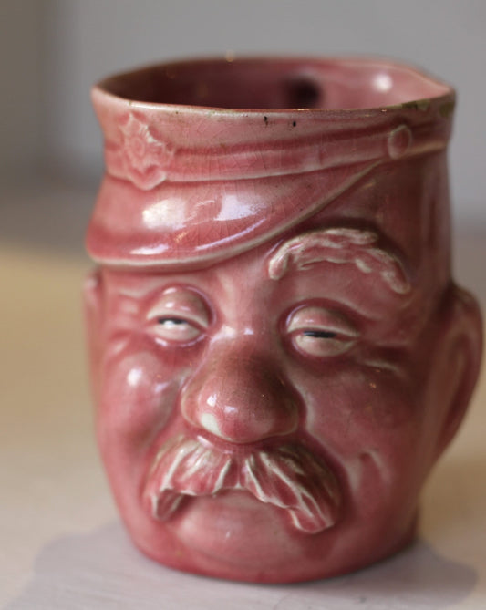 A Vintage Dusky Pink Glazed Military Mug in The Form of Bruce Bairnsfather's Old Bill, 11.5cm high