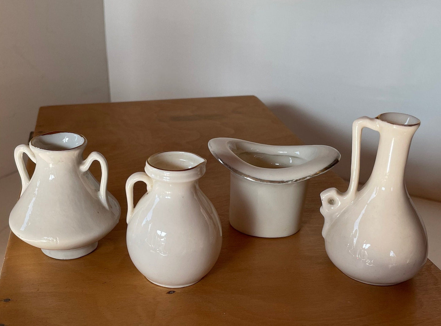 Four Crest Ware Pieces From Places Around The UK  - a W.H Goss Crest Ware Essex Jug, Gravesend Top Hat, Two Southend -On -Sea Jugs