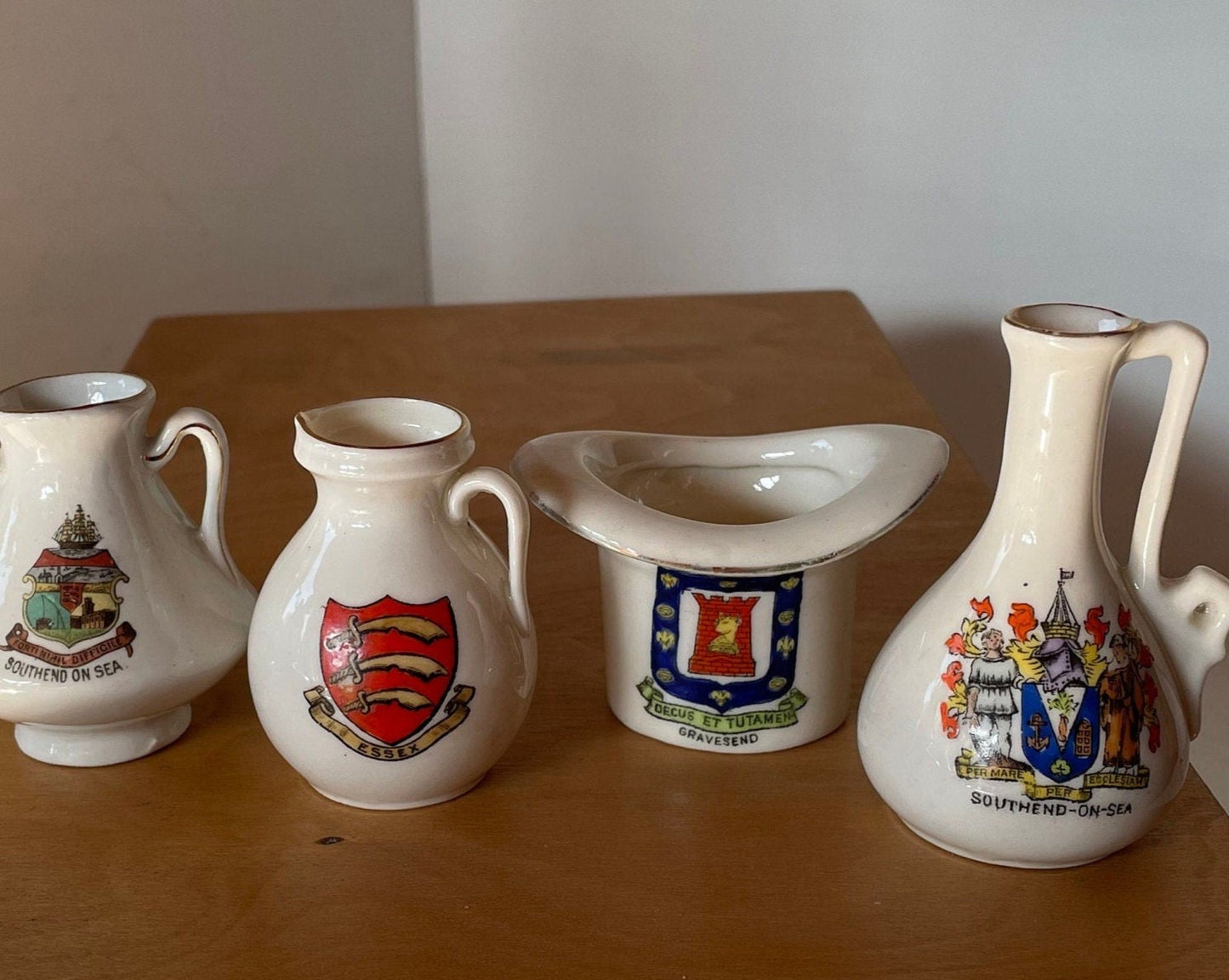 Four Crest Ware Pieces From Places Around The UK  - a W.H Goss Crest Ware Essex Jug, Gravesend Top Hat, Two Southend -On -Sea Jugs