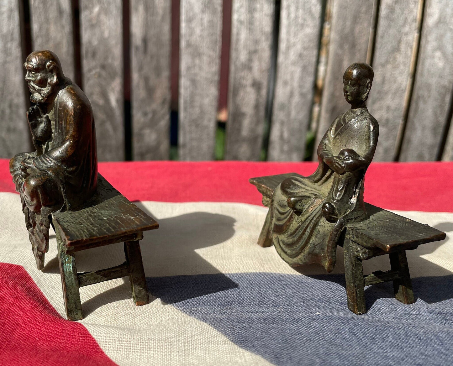 A Close Pair of Chinese Patinated Copper Bronze Figures of Scholars on Benches, the Largest 7.5cm Wide