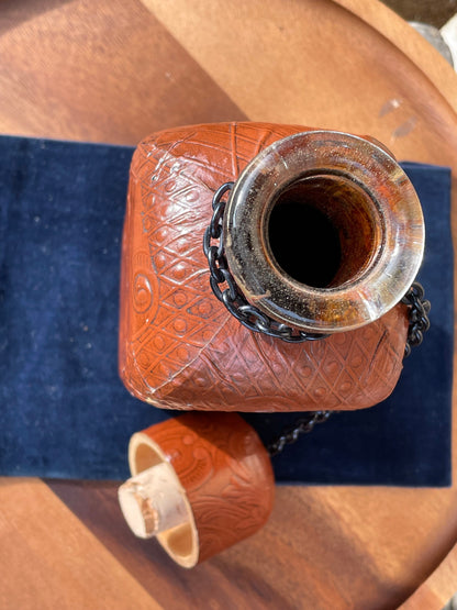 A vintage leather bound decanter with embossed imagery of Don Quixote author Miguel de Cervantes and Spanish text 27cm tall