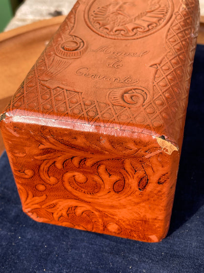 A vintage leather bound decanter with embossed imagery of Don Quixote author Miguel de Cervantes and Spanish text 27cm tall