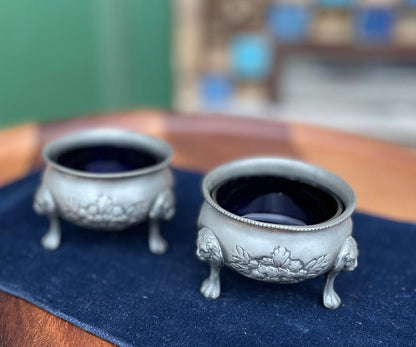 A pair of antique pewter salts with Bristol blue glass liners and lion feet 6.5cm diameter