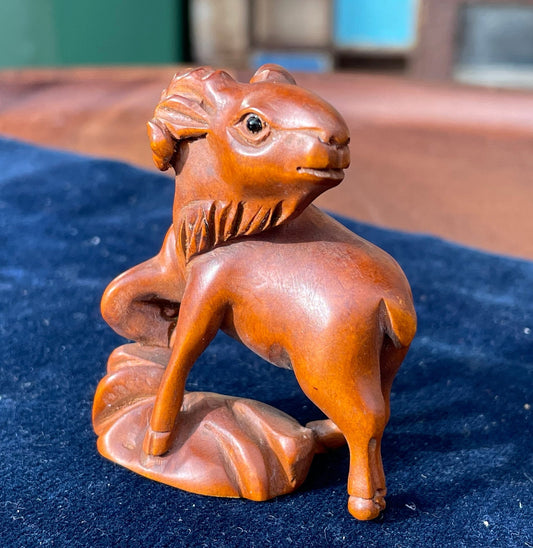 A  Japanese hardwood hand carved Ram netsuke with glass eyes 5cm tall