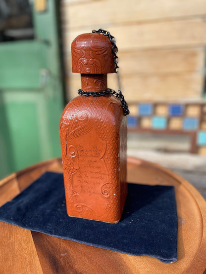 A vintage leather bound decanter with embossed imagery of Don Quixote author Miguel de Cervantes and Spanish text 27cm tall